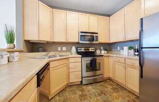 A kitchen with wooden cabinets and a tile floor.