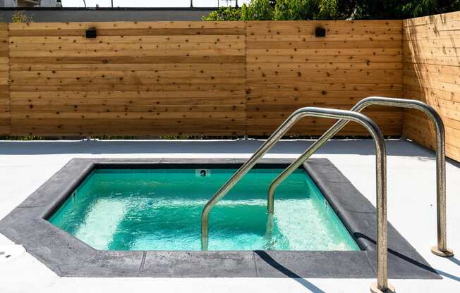 a hot tub with a wooden wall and a stainless steel hand rail