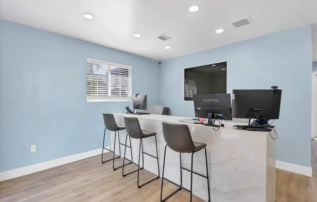 a room with a long desk with three computers on it