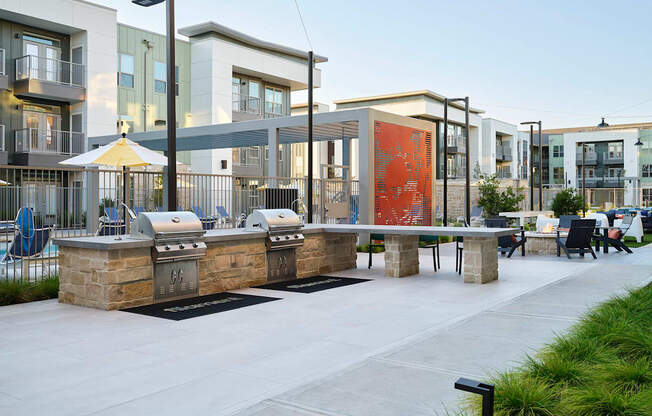 a communal area with tables and chairs and buildings in the background