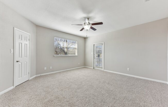A room with a ceiling fan and carpeted floor.