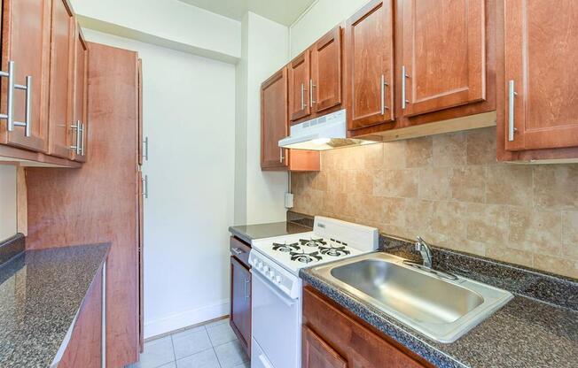 kitchen with wood cabinetry and tile backsplash at the klingle apartments in washignton dc