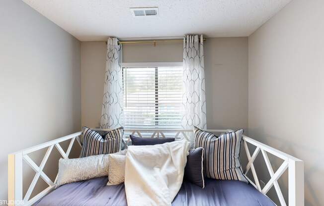 a small bedroom with a bed with pillows and a window