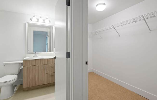A white bathroom with a toilet, sink, and a cabinet.