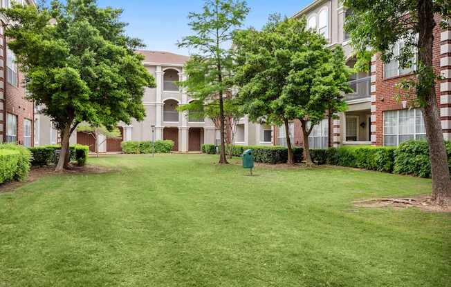 A grassy courtyard surrounded by apartment buildings.