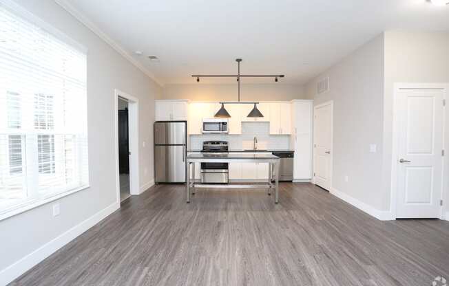 a spacious living room with a kitchen and a large window at Century Baxter Avenue, Louisville, KY