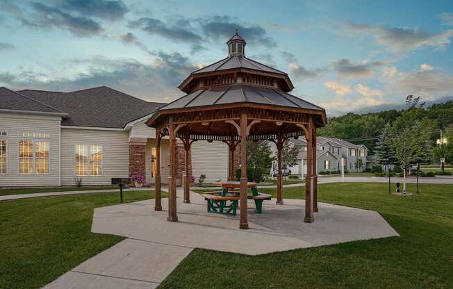 Private gazebo surrounded by lush green lawn with walkway leading to building.