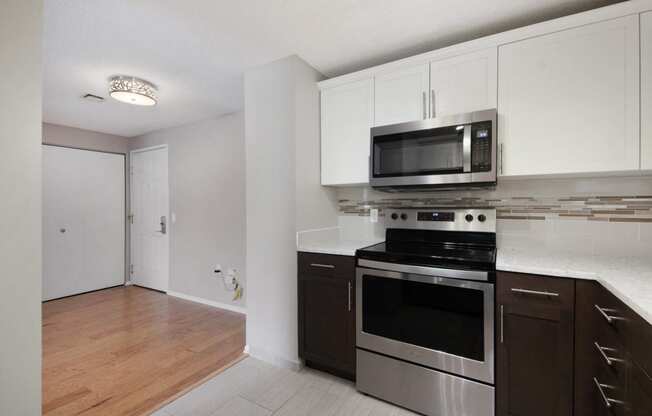 an empty kitchen with stainless steel appliances and white cabinets