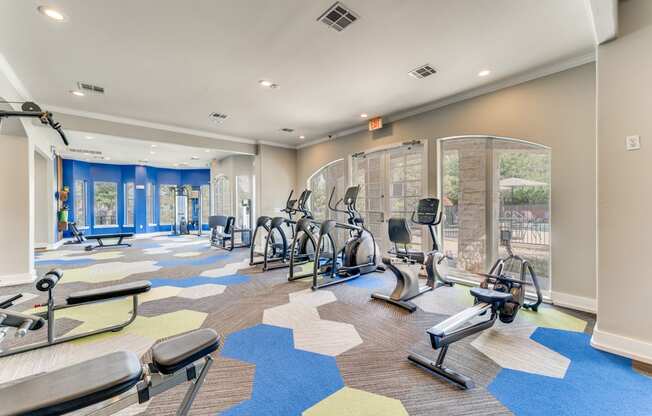 a gym with cardio machines and weights on the floor at the community center