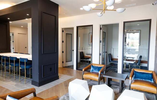 A modern living room with a dark wood fireplace and blue chairs.