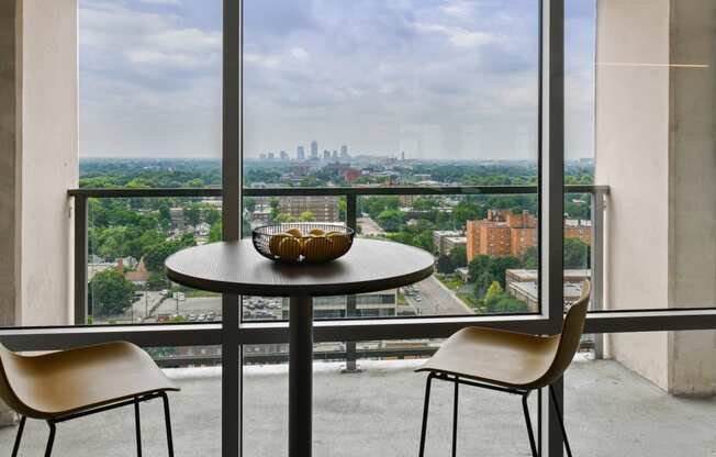 a table and chairs in front of a window with a view of the city