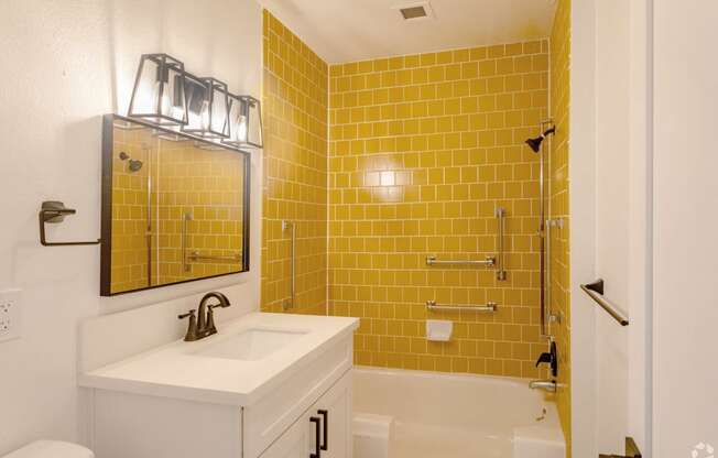 a bathroom with yellow tile and a sink and a shower