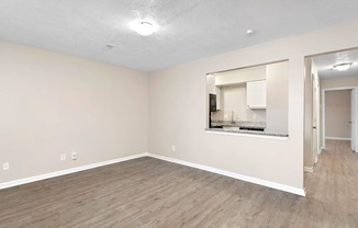 an empty living room with a mirror and a kitchen