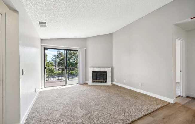 an empty living room with a fireplace and a door to a balcony