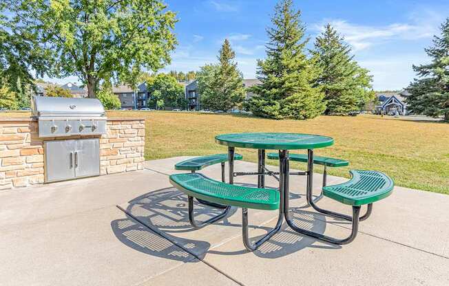 a patio with a picnic table and a barbecue grill