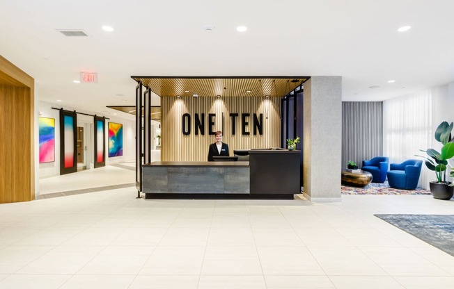 a man sitting at a desk in a lobby with a reception desk at One Ten Apartments, Jersey City , NJ, 07310