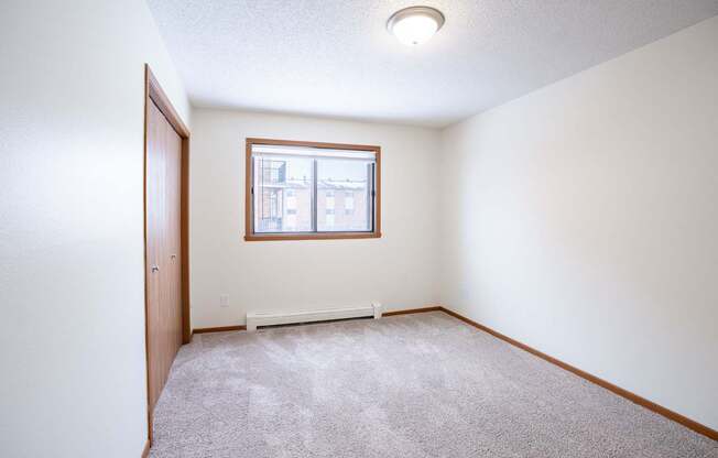 A room with a carpeted floor and a window. Fargo, ND Westwood Estates