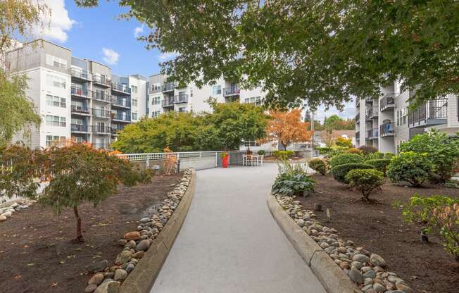 an empty park with trees and buildings in the background