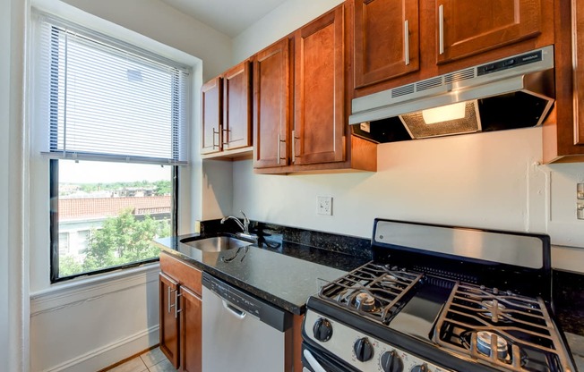 kitchen with stainless steel appliances, wood cabinetry and large window at the shawmut apartments in washington dc