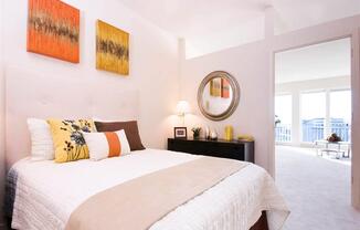 A bedroom with a large bed and two paintings on the wall.