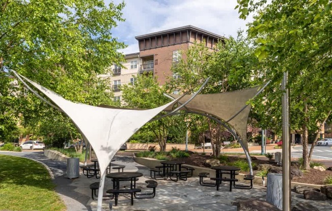 A park with a white canopy and picnic tables.