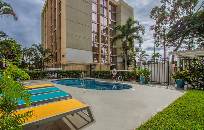 a resort style pool is next to a tall building at Palms of Kilani Apartments, Wahiawa, Hawaii