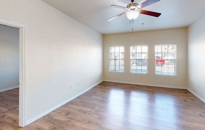 an empty living room with a ceiling fan and a window