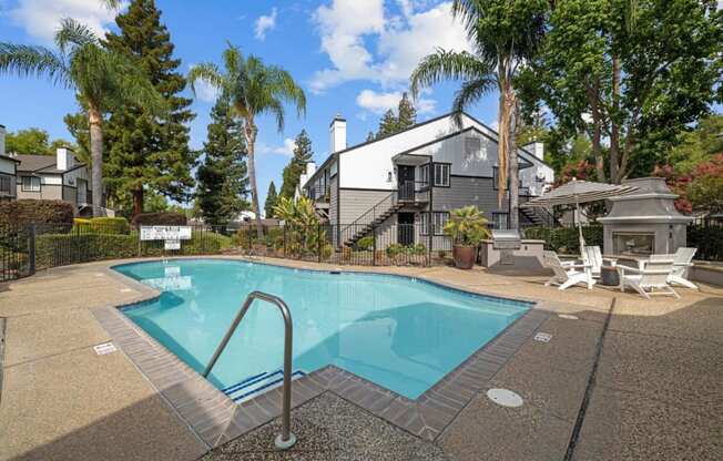 a swimming pool with chairs and a house in the background