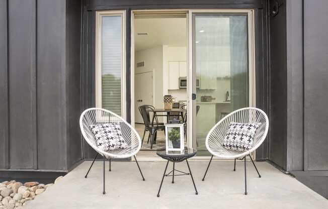 a patio with two chairs and a table and a sliding glass door