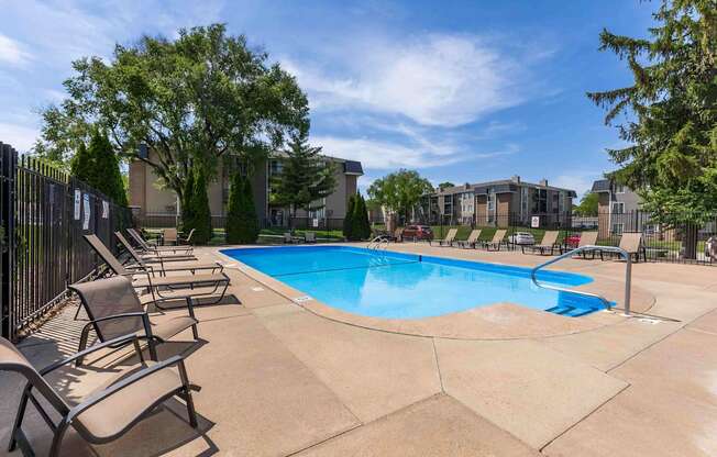 A pool surrounded by chairs and trees.