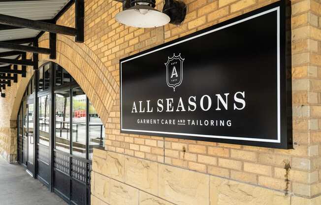 black sign with white text in a regal design that reads "All Seasons Garment Care and Tailoring"