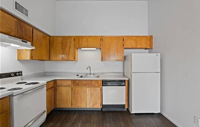 A kitchen with white appliances and wooden cabinets.