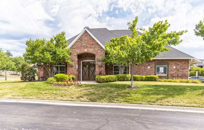 the front of a brick house with trees and grass