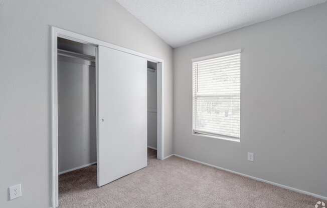 an empty bedroom with a closet and a window