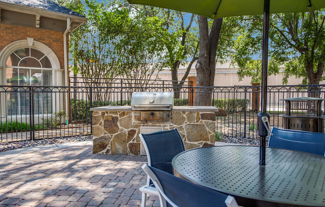 A patio with a table, chairs and a stone pillar.