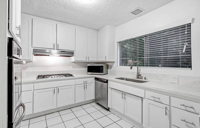 a white kitchen with white cabinets and a sink