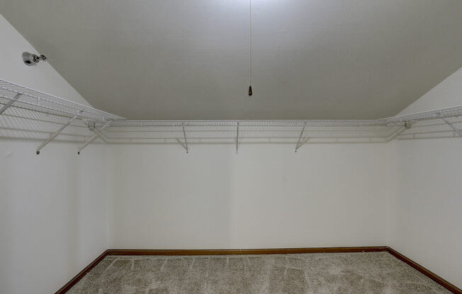 an empty room with white walls and a hanging light on the ceiling