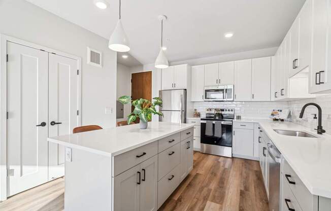 A modern kitchen with white cabinets and a wooden floor.