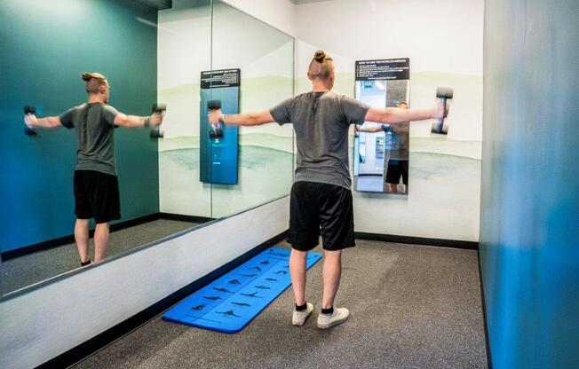 a man doing a dumbbell exercise in a mirror in a gym