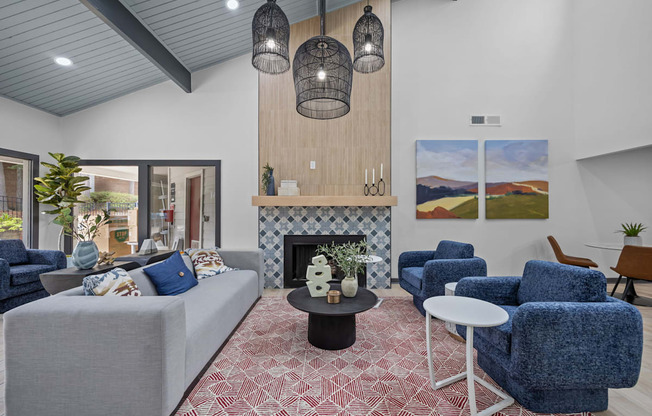 A living room with a grey couch, blue chairs, and a fireplace.