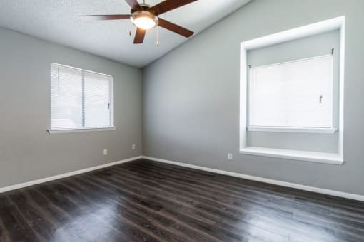 an empty living room with a ceiling fan and a window