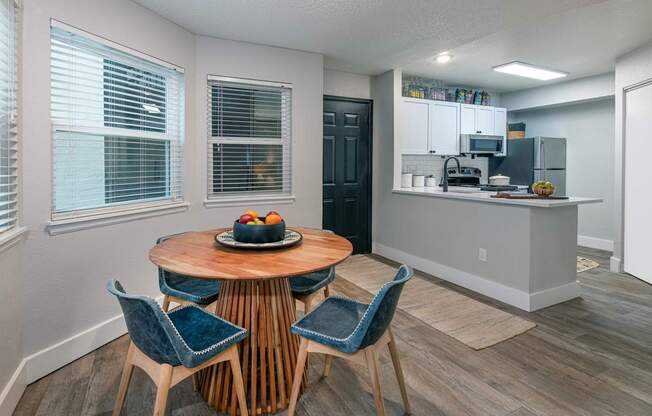 A kitchen with a table and chairs in the foreground and a refrigerator in the background.
