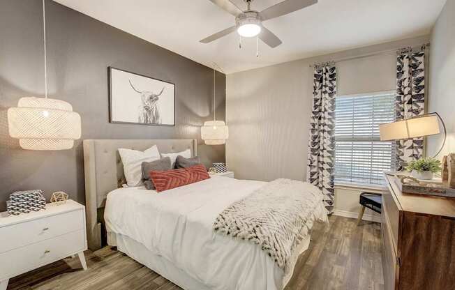 A bedroom with a bed, nightstand, and a ceiling fan.
