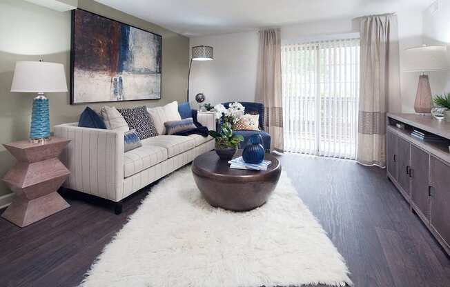 Ardenne Apartment living room with white rug, couch and sliding glass doors to outside