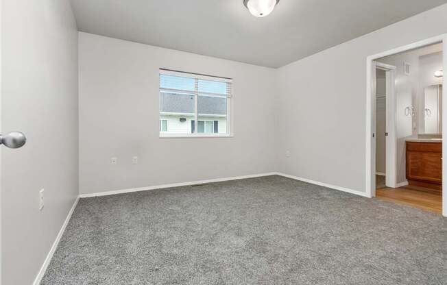 A room with a window and a door leading to another room.