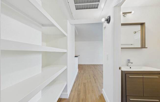 A white hallway with a mirror and a sink.