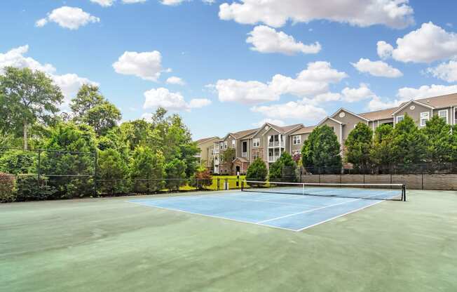 an outdoor tennis court with apartments in the background