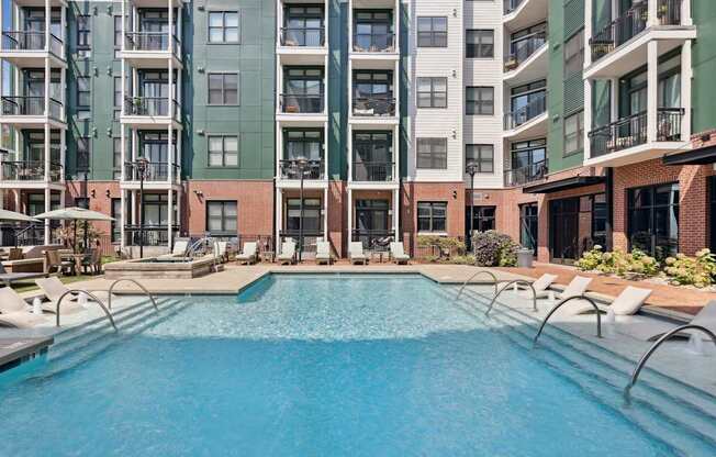 A large swimming pool in front of apartment buildings.
