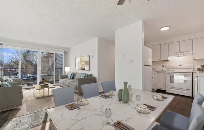 a living room with a table and chairs and a kitchen with a sliding glass door