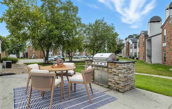 A patio with a table and chairs and a grill.